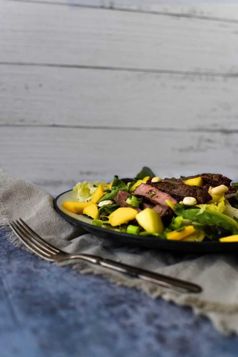 Side view of steak salad with mango