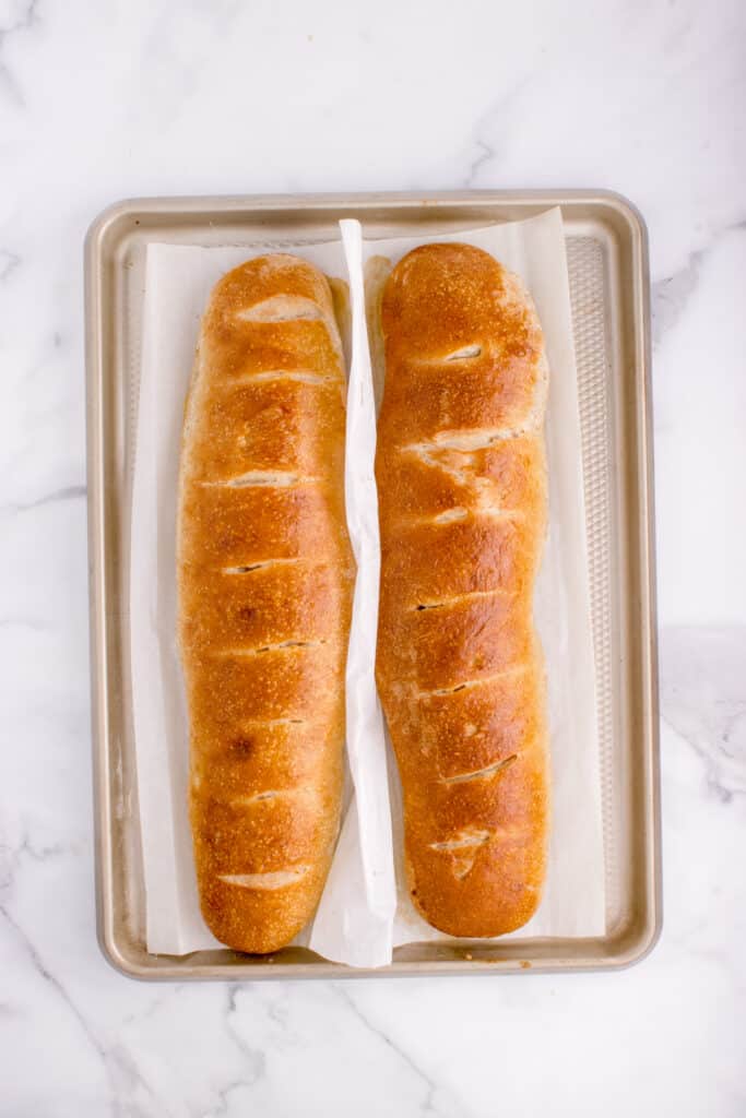 two loaves of freshly baked french bread on cookie sheet