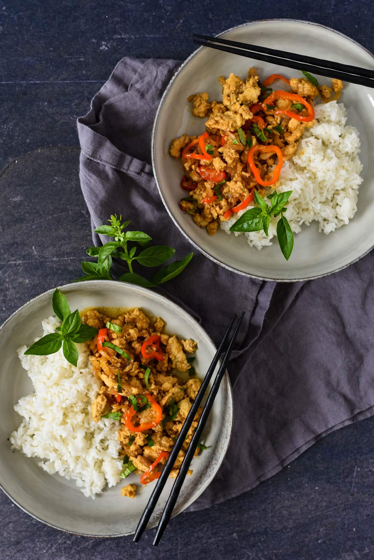 two plates of rice and basil chicken with chopsticks